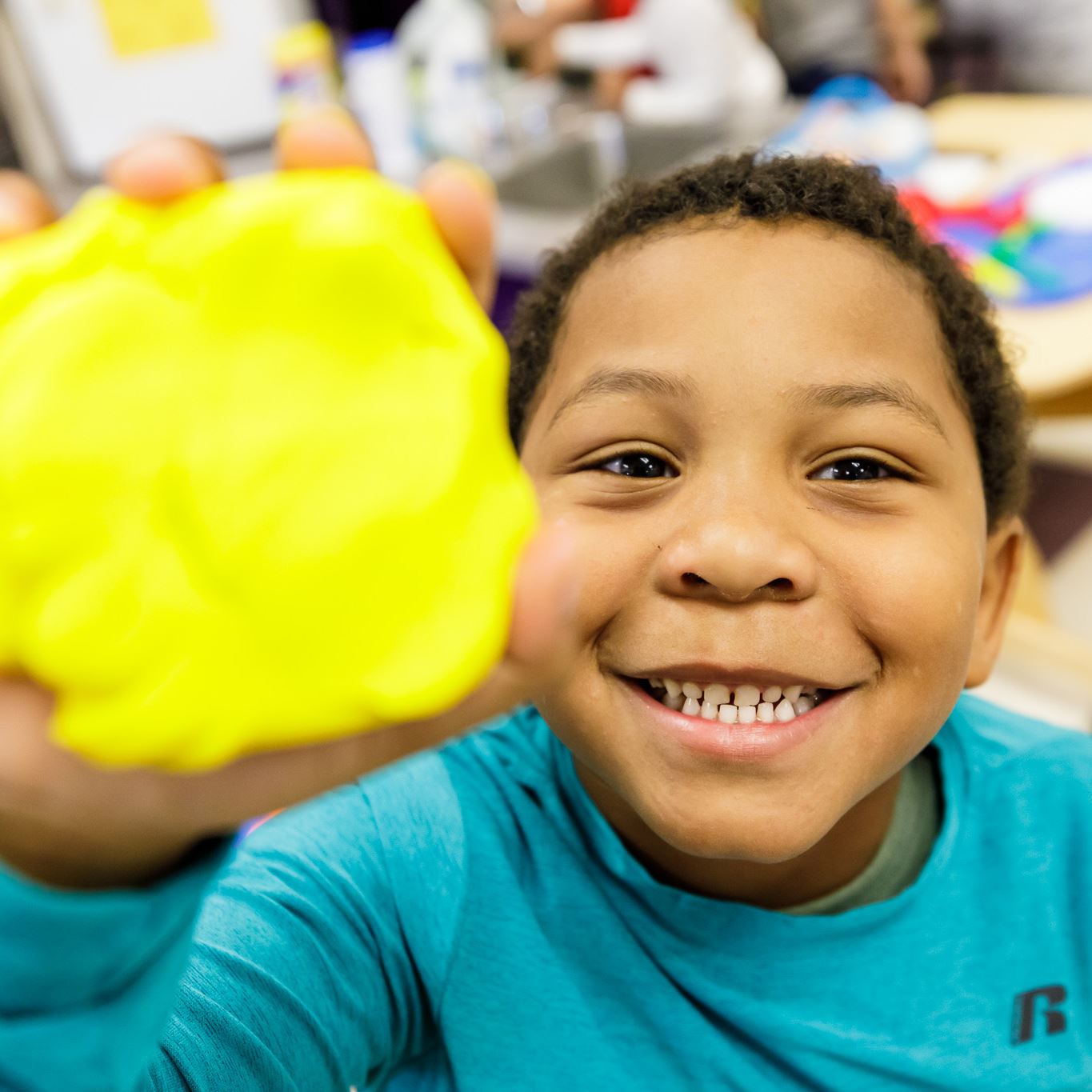 boy holding play doh and smiling